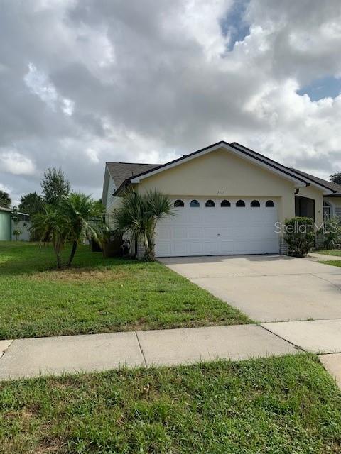 A single-story house with a white garage door and a palm tree in the yard — 7817 LAUREL OAK LANE, KISSIMMEE, FL