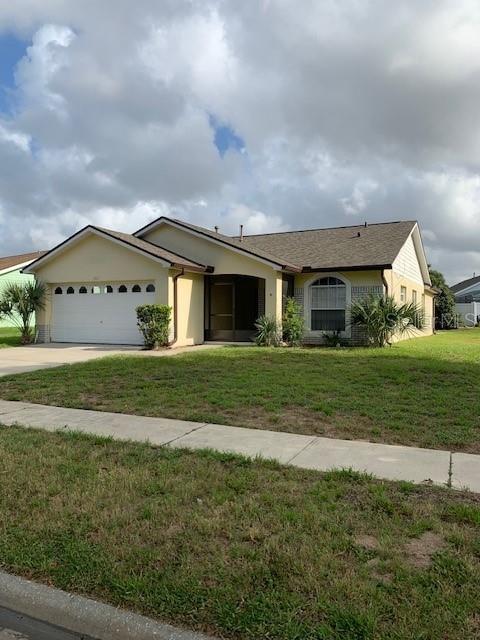 A single-story house with a beige exterior, a two-car garage, and a screened-in entryway — 7817 LAUREL OAK LANE, KISSIMMEE, FL