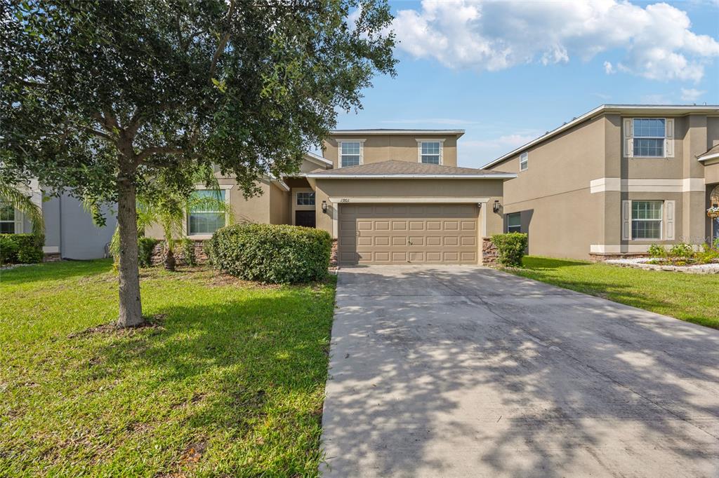A two-story suburban house with a tan stucco exterior, a two-car garage, and a driveway — 13801 NEWPORT SHORES DRIVE, HUDSON, FL