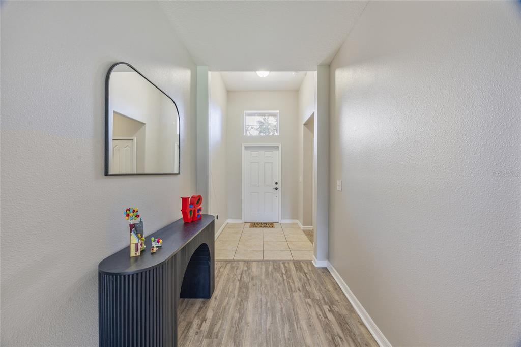 An entryway features a dark arched console table, a wall mirror, and tile flooring — 13801 NEWPORT SHORES DRIVE, HUDSON, FL
