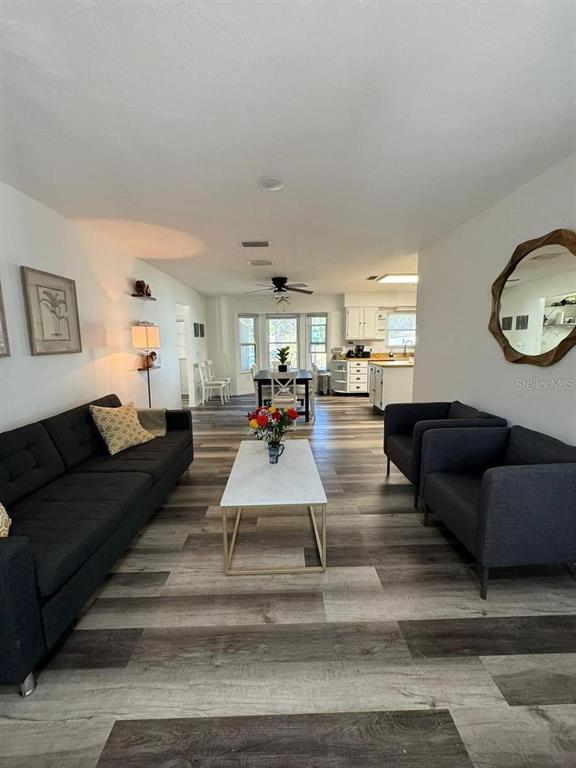 A living room with dark gray furniture, a white coffee table, and wood-look flooring — 20164 SE 115TH COURT, INGLIS, FL