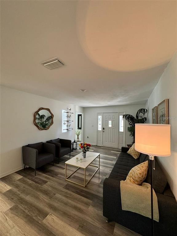 A living room features gray furniture, a white coffee table, and wood-look flooring — 20164 SE 115TH COURT, INGLIS, FL