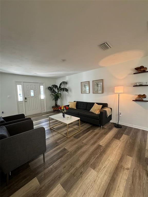 A living room features dark gray sofas, a white coffee table, and wood-look flooring — 20164 SE 115TH COURT, INGLIS, FL