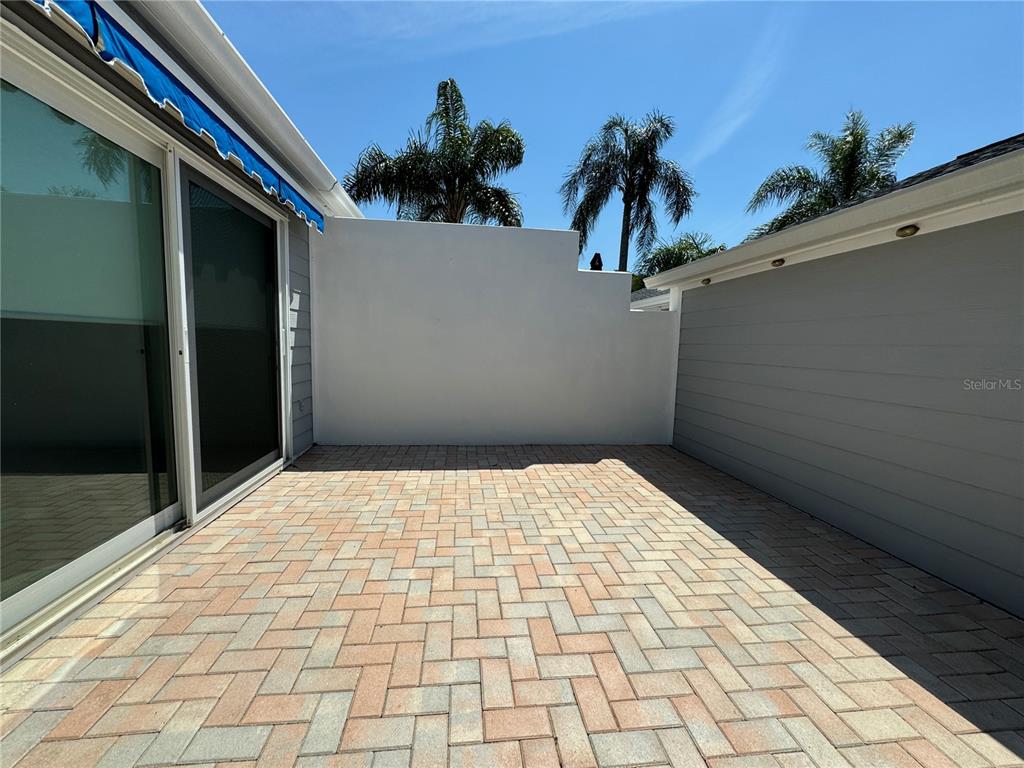 A paved patio area is enclosed by a white wall and gray siding — 1005 PELICAN COURT, BRADENTON, FL