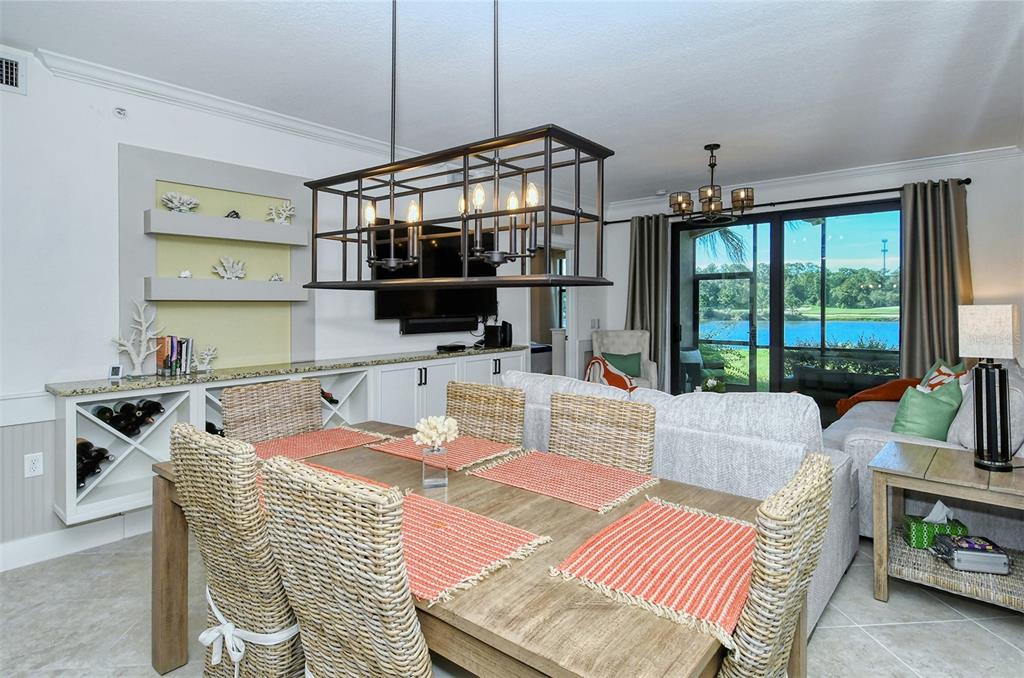 A dining area with a wicker chair set and a large metal chandelier overlooks a lake — 16706 VARDON TERRACE UNIT 105, BRADENTON, FL