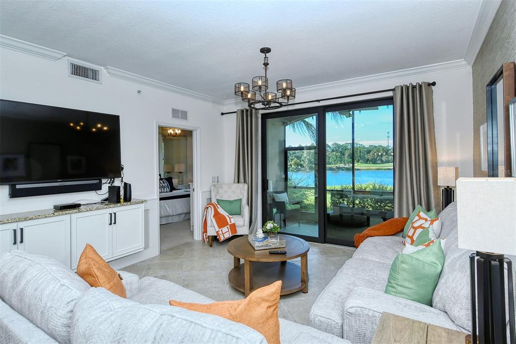 A living room features a large television, a round coffee table, and sliding glass doors — 16706 VARDON TERRACE UNIT 105, BRADENTON, FL