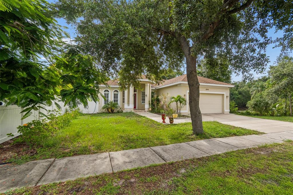 A single-story house with a beige exterior, a two-car garage, and a large front tree — 8040 57TH STREET N, PINELLAS PARK, FL