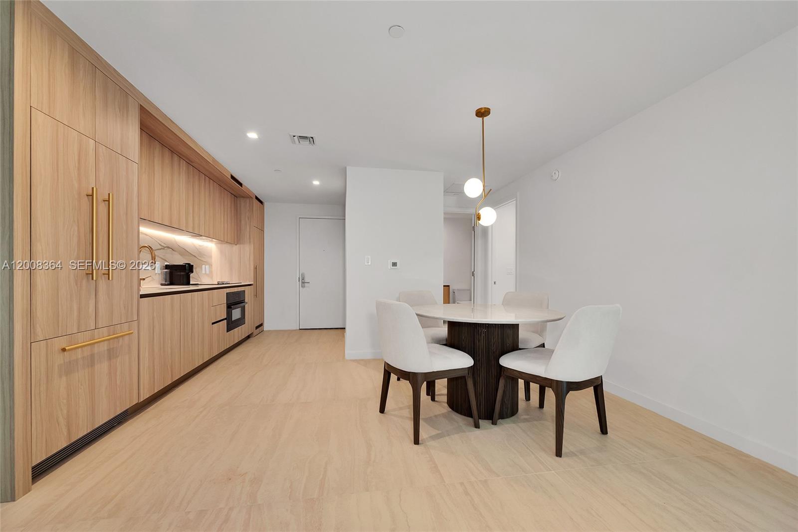 A modern kitchen and dining area feature light wood cabinetry and a round marble table — 77 SE 5 # 1906, Miami FL 33131-2507, MIAMI, FL
