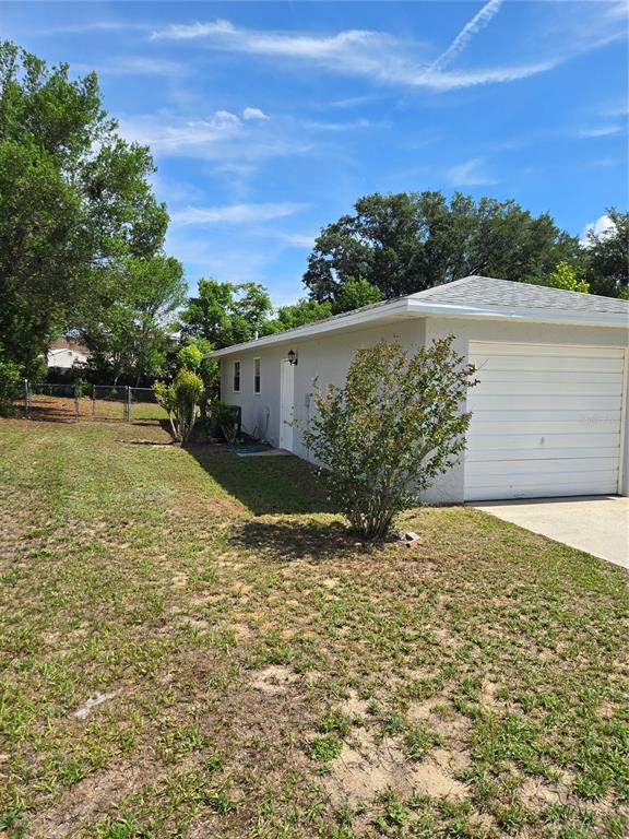 A side view of a house with a white garage door and a grassy yard — 4 CLEAR WAY, OCALA, FL