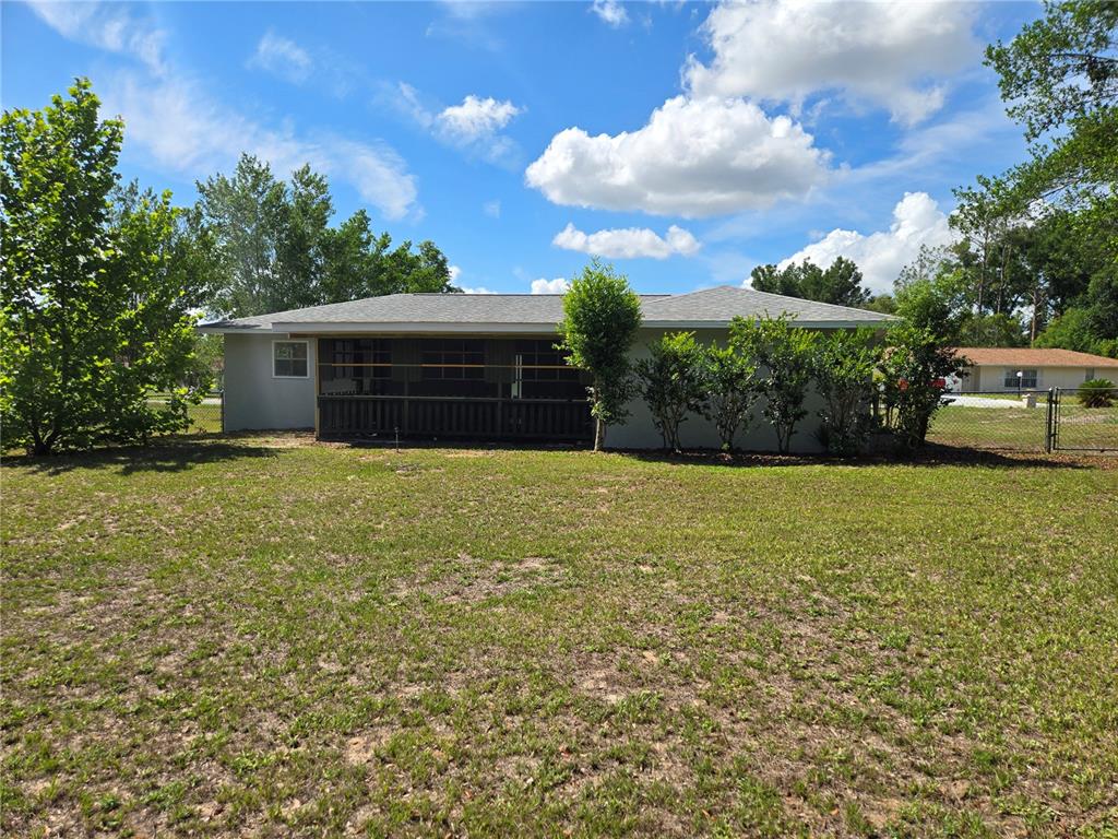The rear exterior of a single-story house features a screened-in porch and a large yard — 4 CLEAR WAY, OCALA, FL