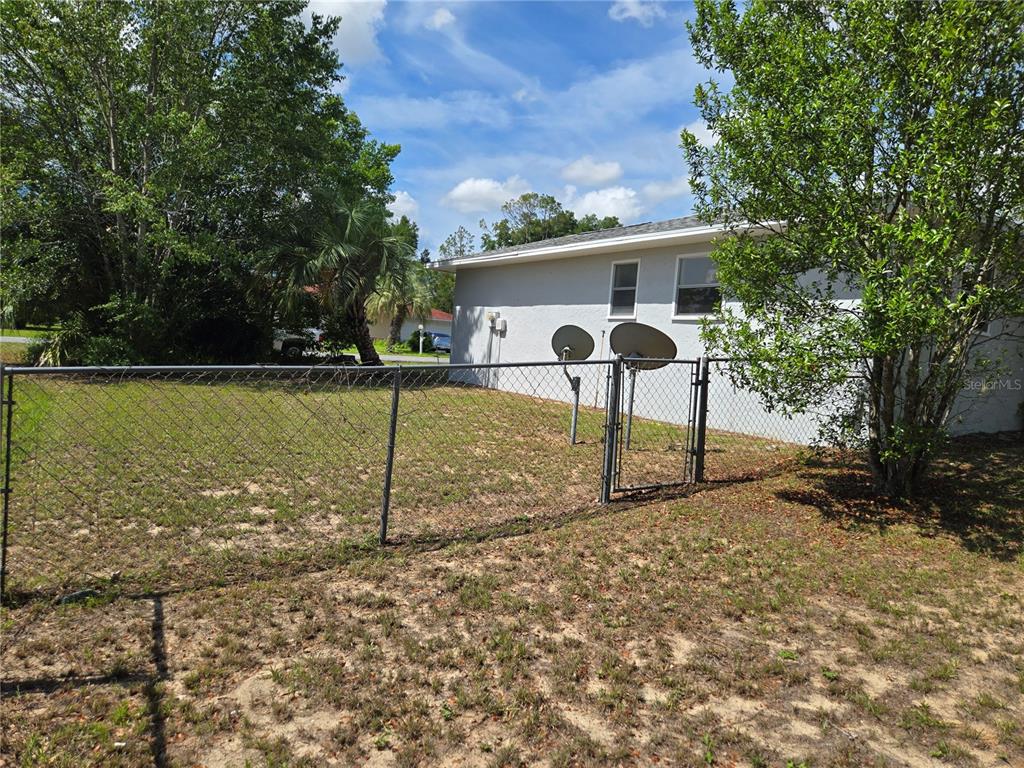 A chain-link fence encloses a grassy backyard next to the side of a house — 4 CLEAR WAY, OCALA, FL