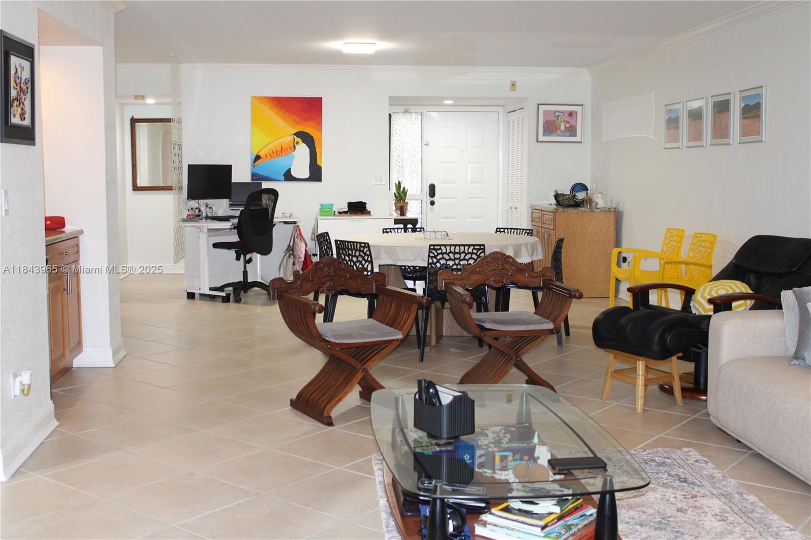 An open-concept living and dining area features tile flooring, a desk, and wooden chairs — 16051 Blatt Blvd # 106, Weston FL 33326, WESTON, FL