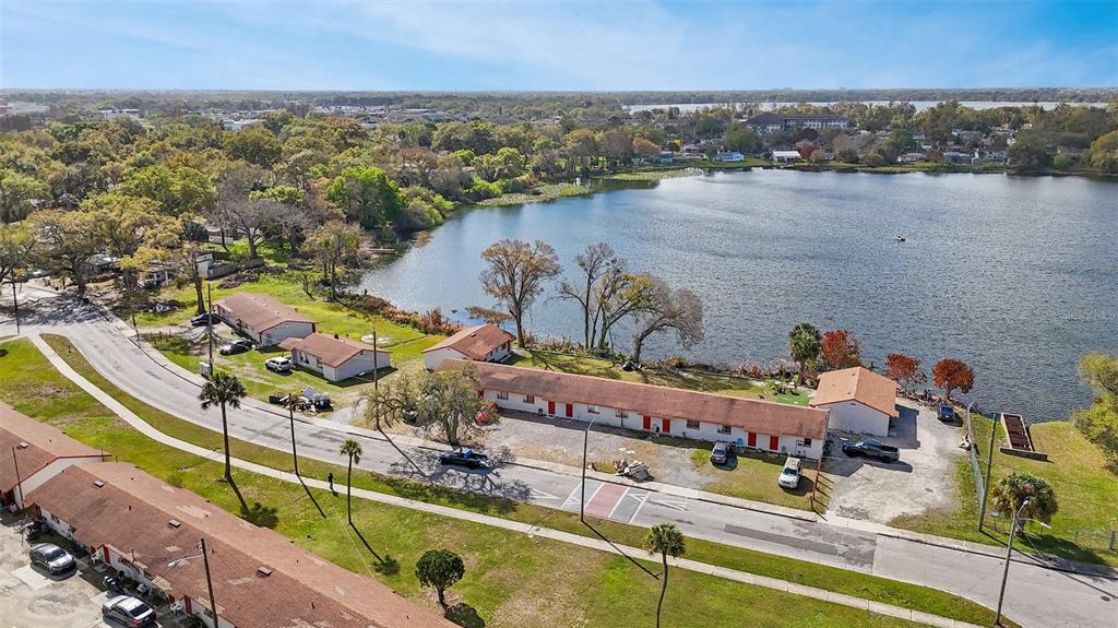 An aerial view shows a long, single-story apartment building situated beside a large lake — 2222 W SOUTH STREET, ORLANDO, FL