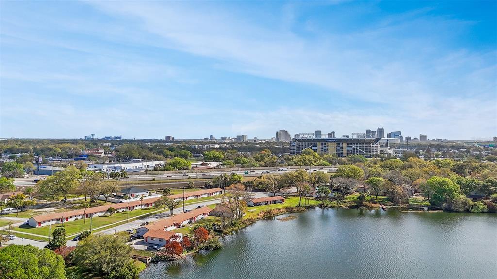 An aerial view shows a lake, low-rise apartment buildings, a highway, and a distant city skyline — 2222 W SOUTH STREET, ORLANDO, FL