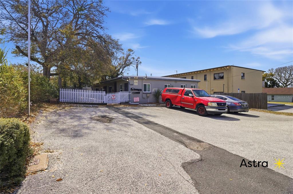 A gravel parking lot sits in front of a single-story building with a white fence — 1429 LAURA STREET, CLEARWATER, FL