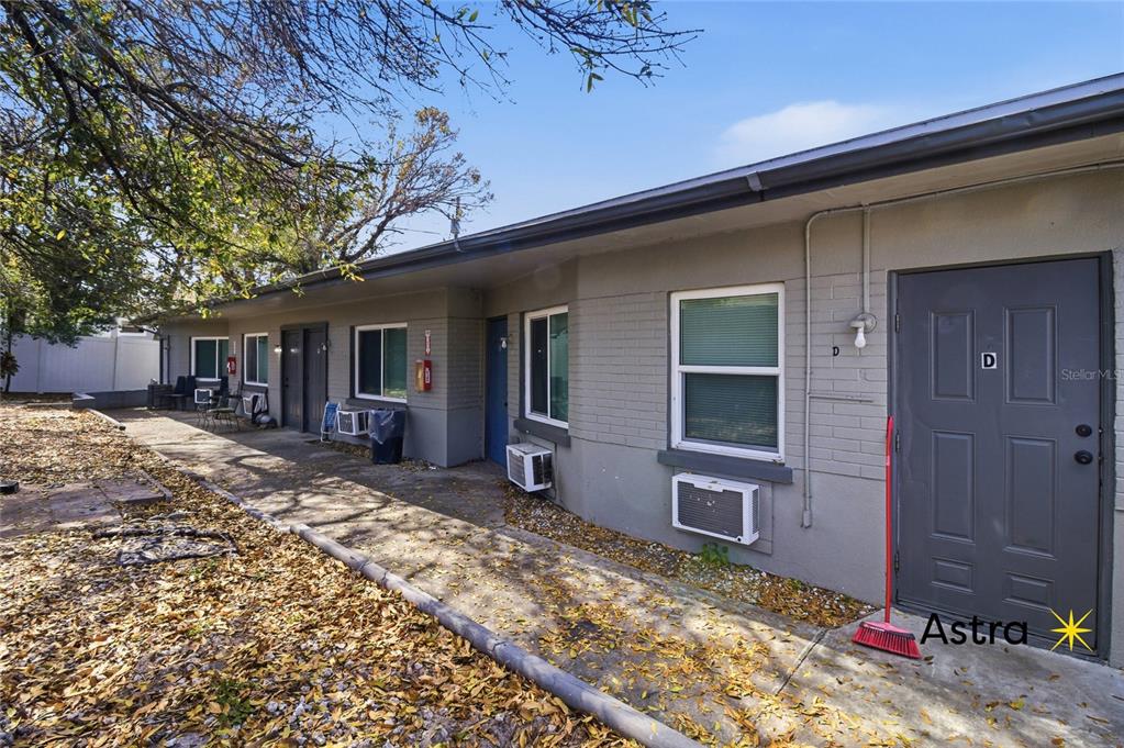 The exterior of a single-story apartment building features gray painted brick walls and unit doors — 1429 LAURA STREET, CLEARWATER, FL