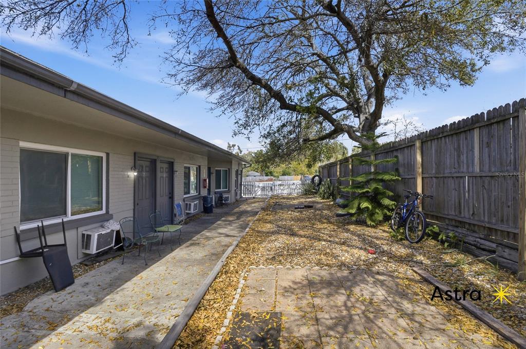 A paved walkway runs alongside a single-story building with a gravel yard and wooden fence — 1429 LAURA STREET, CLEARWATER, FL