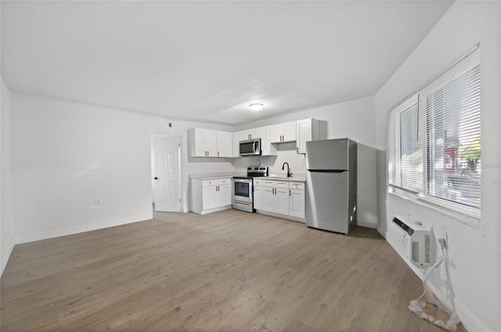 A kitchen with white cabinets, stainless steel appliances, and light wood-look flooring — 1429 LAURA STREET, CLEARWATER, FL