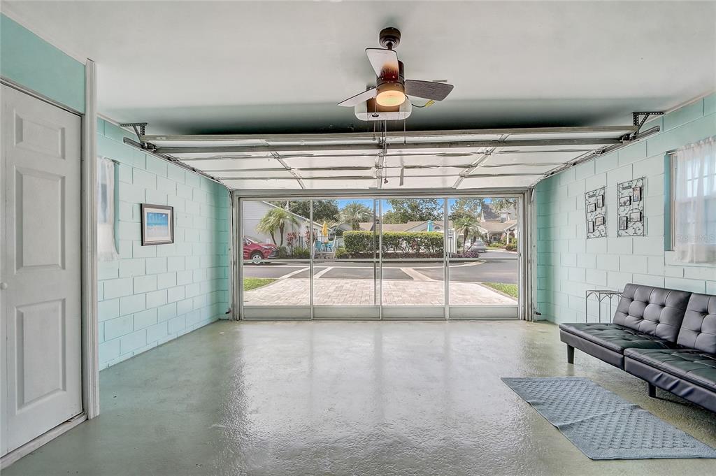 A garage with light blue painted block walls, a ceiling fan, and a screen door — 399 DIVISION STREET, CLERMONT, FL