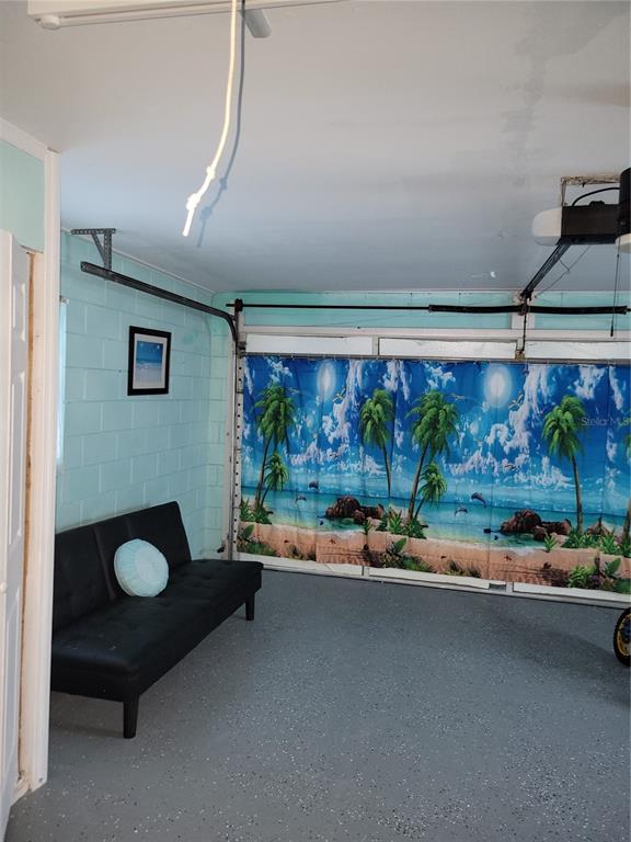 A garage with light blue painted block walls, a black futon, and a beach-themed curtain — 399 DIVISION STREET, CLERMONT, FL