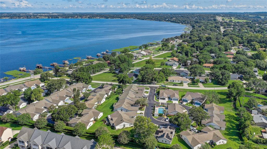 An aerial view shows a residential neighborhood with townhomes and houses near a large lake — 399 DIVISION STREET, CLERMONT, FL