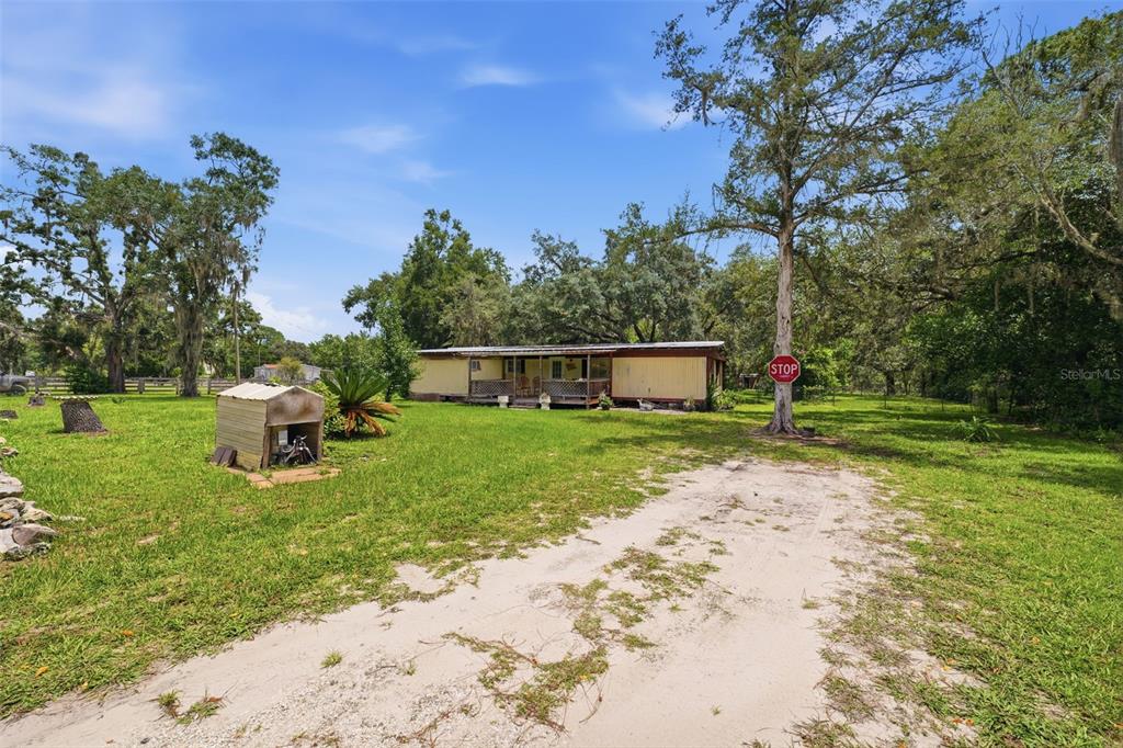 A single-story mobile home with a front porch sits on a grassy, wooded lot — 6106 DESALES STREET, BROOKSVILLE, FL