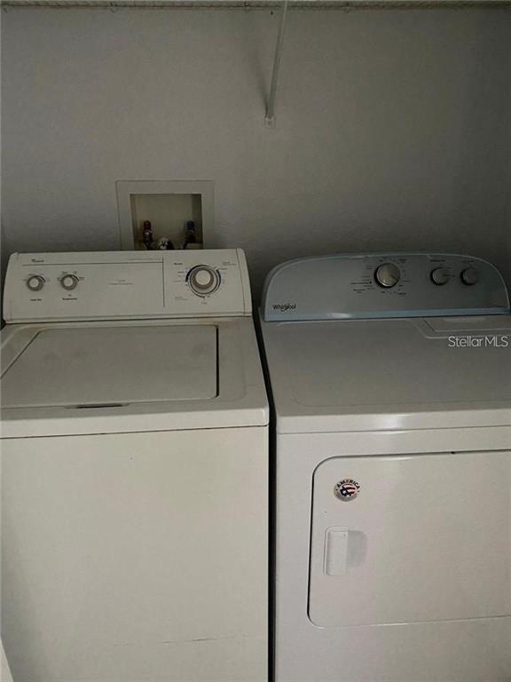 A laundry closet contains a white top-loading washing machine and a matching dryer — 3725 CASTLE PINES LANE UNIT 4337, ORLANDO, FL