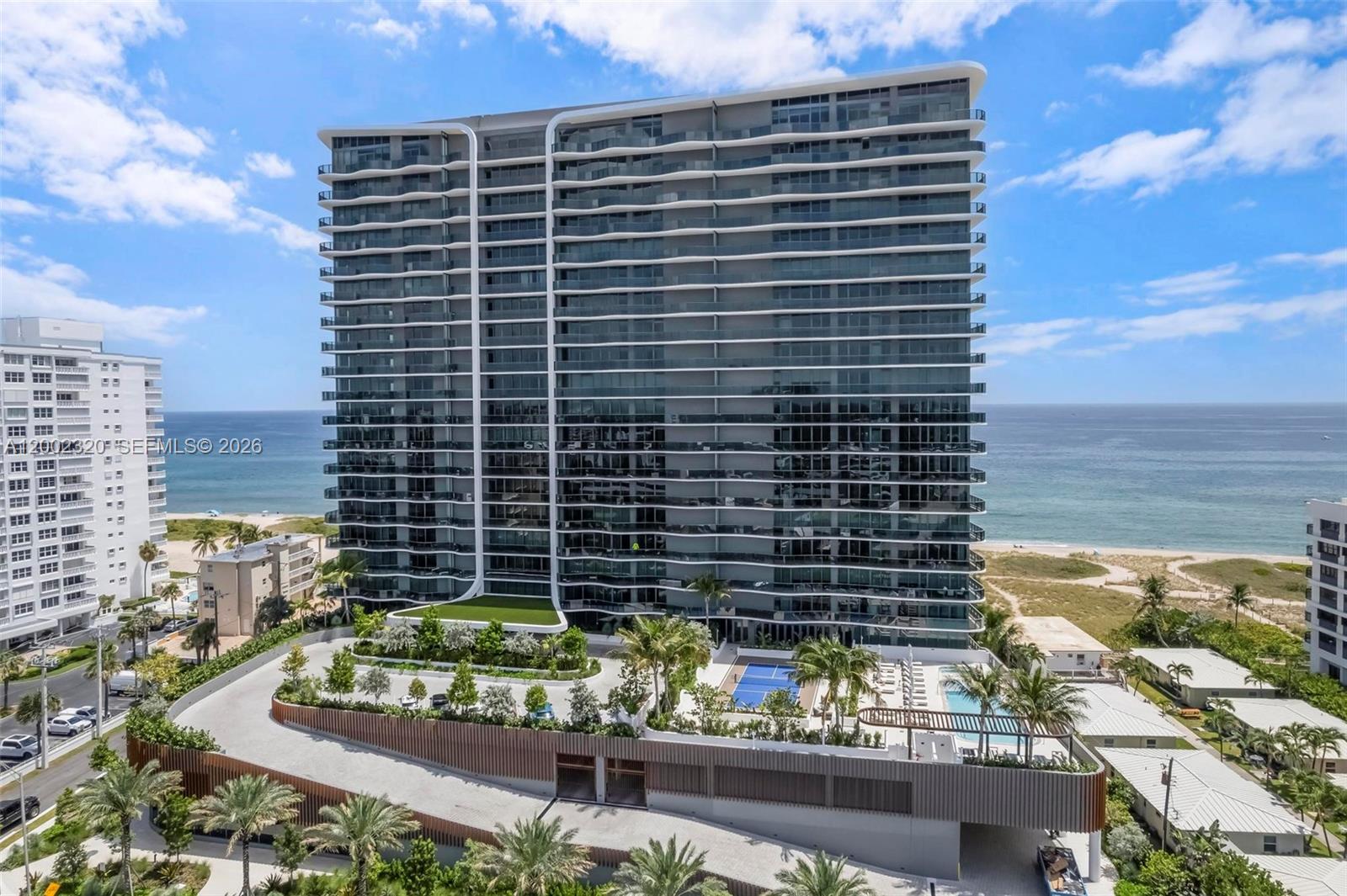 An aerial view of a modern high-rise condominium building situated along a sandy beach — 900 N Ocean Blvd # 1202, Pompano Beach FL 33062, POMPANO BEACH, FL