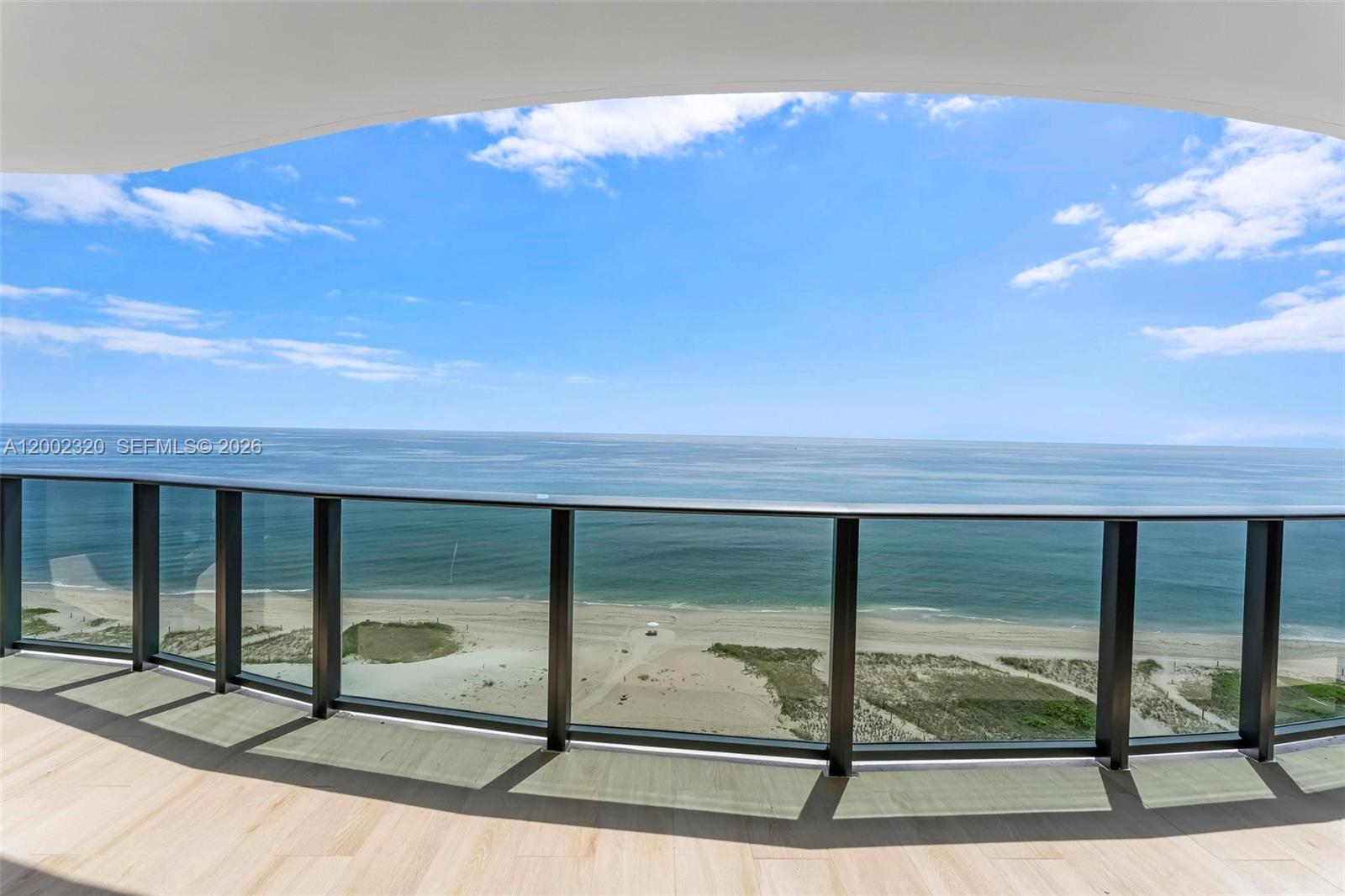 A balcony with a glass railing overlooks a sandy beach and the ocean — 900 N Ocean Blvd # 1202, Pompano Beach FL 33062, POMPANO BEACH, FL