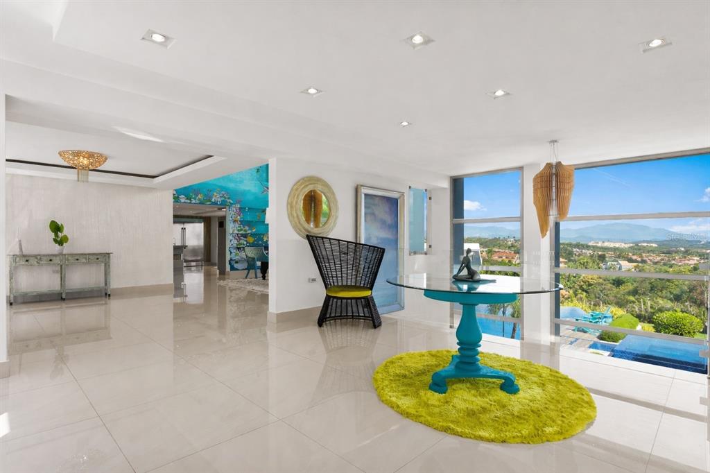 A bright, open-concept living area features white tile floors, a glass table, and mountain views — _ ROBLE VALLEY UNIT 12 / 13, HUMACAO, PR