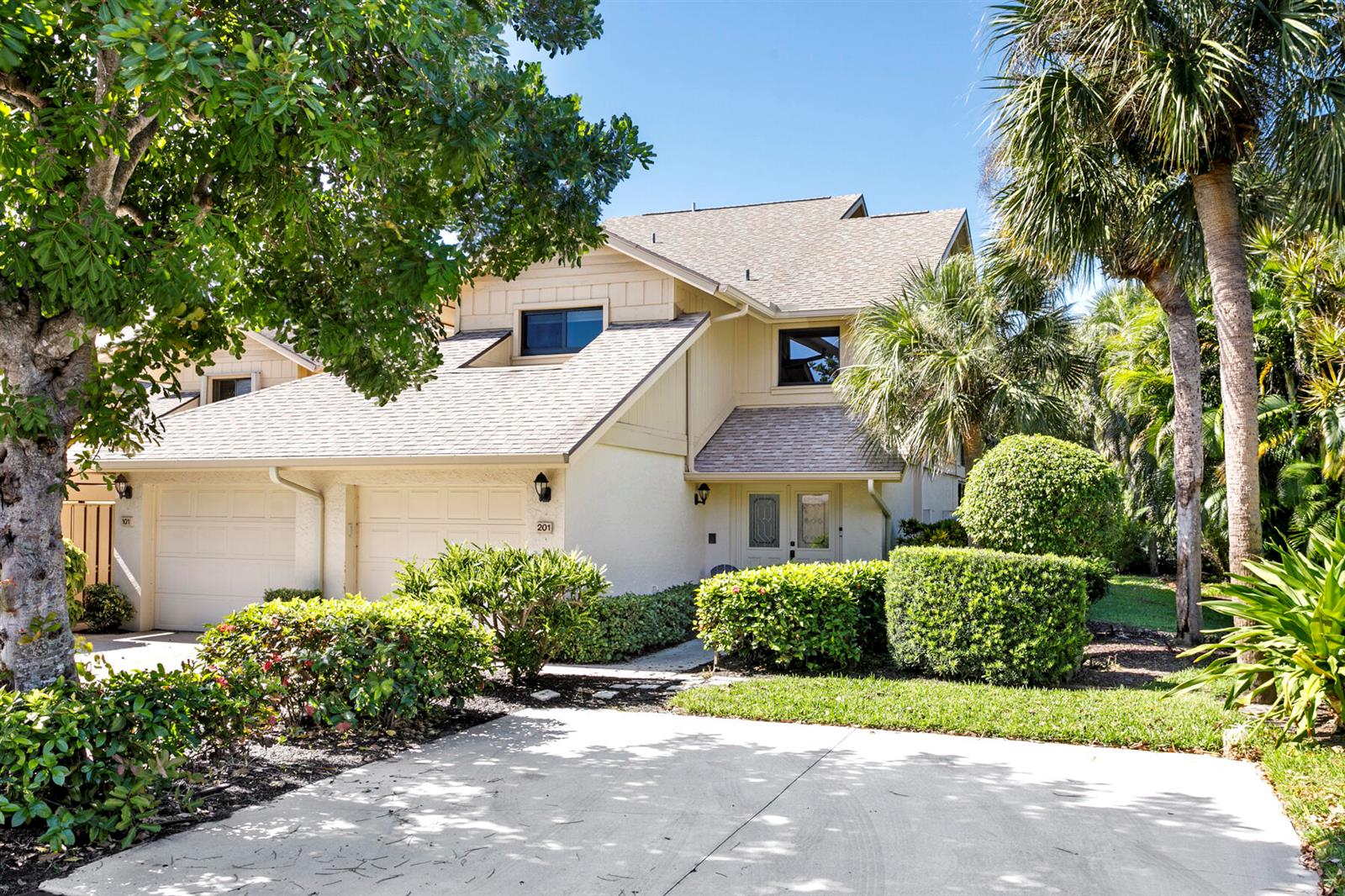 A two-story tan house with a two-car garage, shingled roof, and landscaped front yard — 17137 Waterbend Drive # 201, Jupiter FL 33477, JUPITER, FL