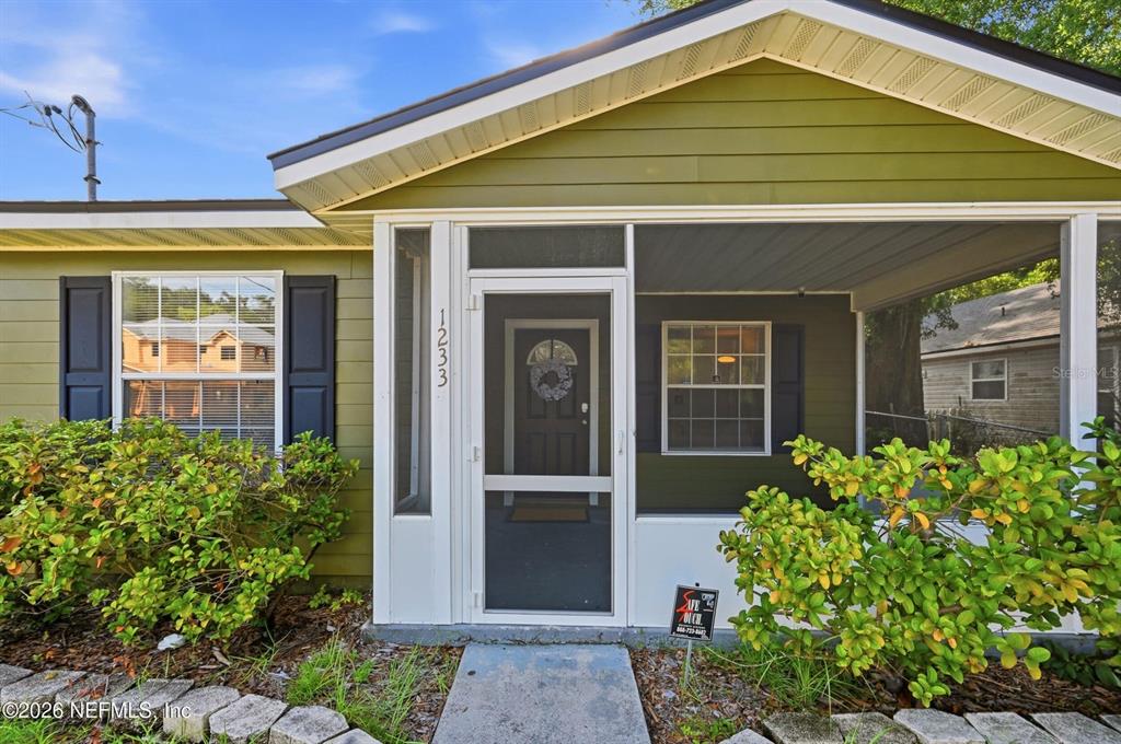 The exterior of a house features a screened-in front porch with green siding and shutters — 1233 VAN BUREN STREET, JACKSONVILLE, FL