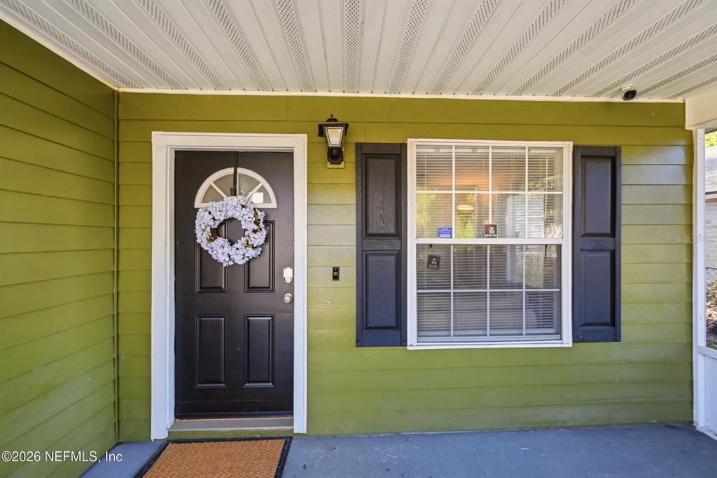 A black front door with a wreath sits beside a window on a green porch — 1233 VAN BUREN STREET, JACKSONVILLE, FL
