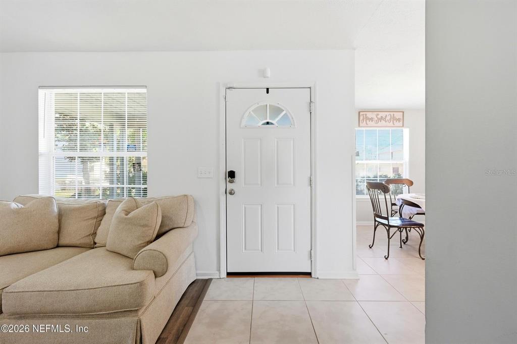 A living room with a beige sofa, a white front door, and a dining area — 1233 VAN BUREN STREET, JACKSONVILLE, FL
