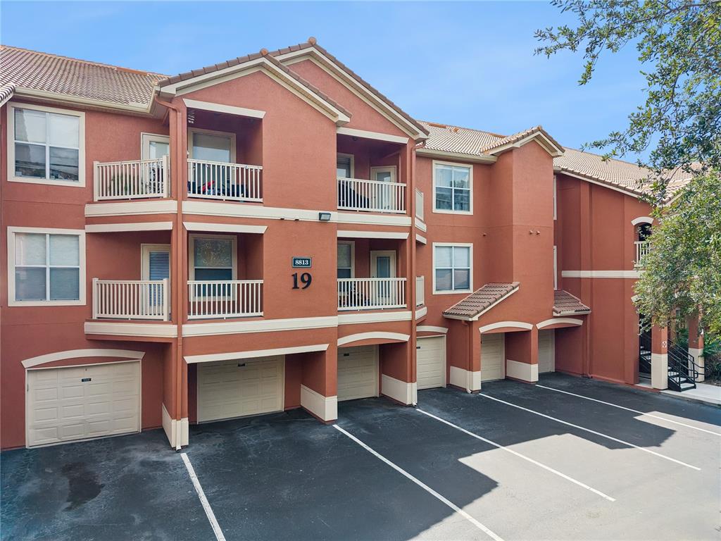 An exterior view of a multi-story apartment building with attached garages and balconies — 8813 VILLA VIEW CIRCLE UNIT 308, ORLANDO, FL