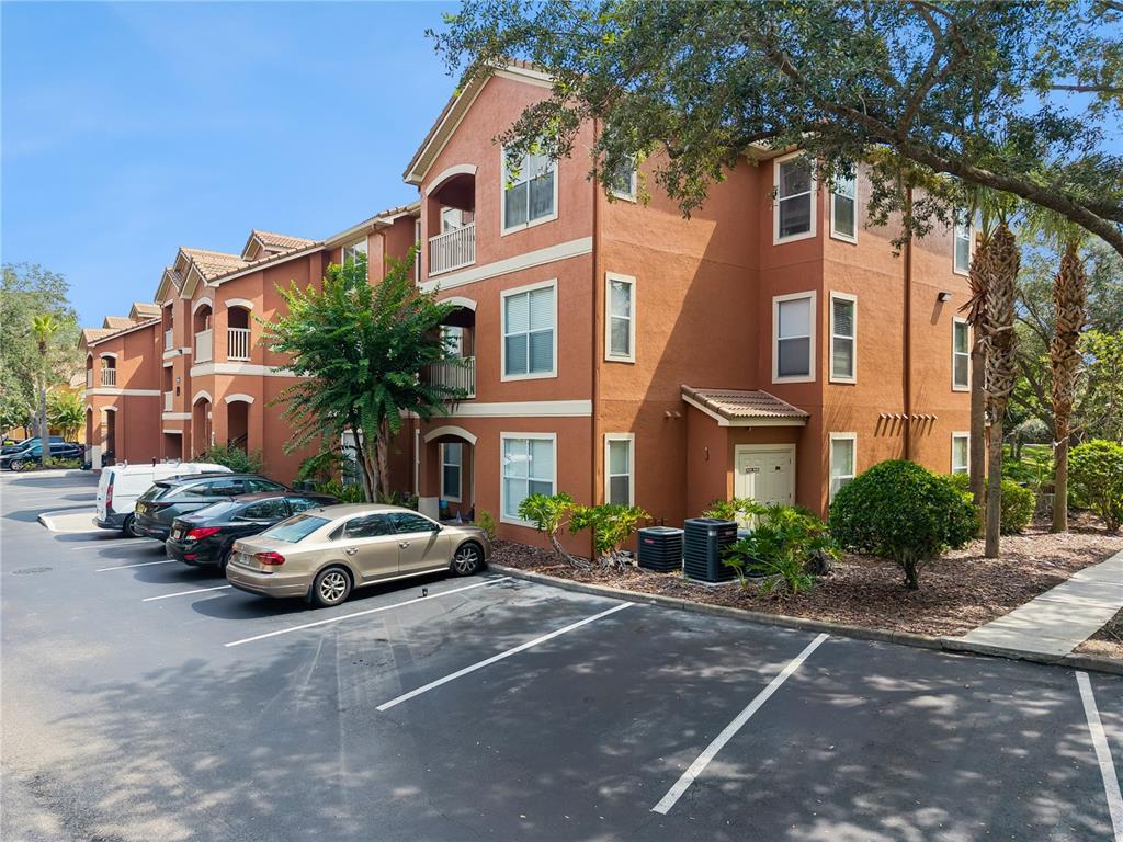 A multi-story apartment building with stucco walls and a parking lot in the foreground — 8813 VILLA VIEW CIRCLE UNIT 308, ORLANDO, FL