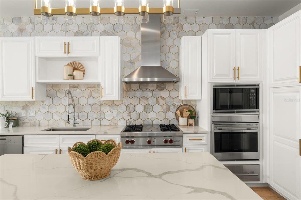 A modern kitchen features white cabinetry, a marble-patterned island, and a hexagonal tile backsplash — 150 E ROBINSON STREET UNIT PH3504, ORLANDO, FL