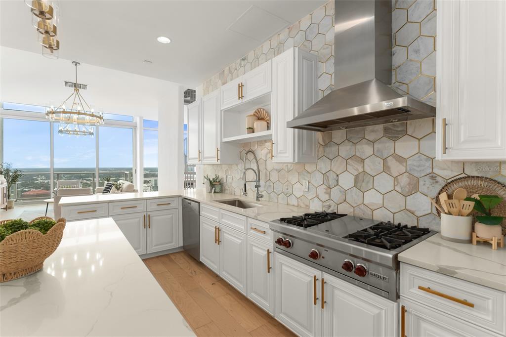A modern kitchen features white cabinetry, marble-style hexagonal backsplash tiles, and a stainless steel range — 150 E ROBINSON STREET UNIT PH3504, ORLANDO, FL