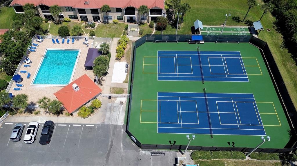 An aerial view shows a swimming pool, a clubhouse, and two tennis courts — 441 BOUCHELLE DRIVE UNIT 202, NEW SMYRNA BEACH, FL