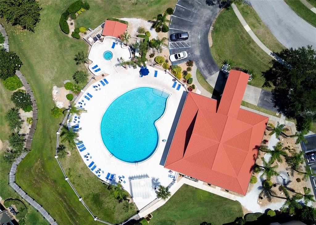 An aerial view shows a community swimming pool, a hot tub, and a clubhouse building — 441 BOUCHELLE DRIVE UNIT 202, NEW SMYRNA BEACH, FL