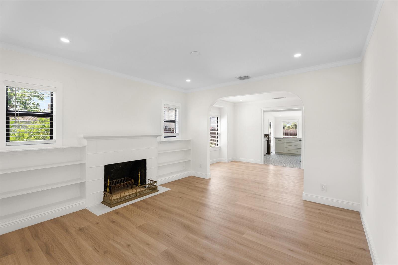 A living room with light wood floors, a white fireplace, and built-in shelving — 517 55th Street, West Palm Beach FL 33407, WEST PALM BEACH, FL