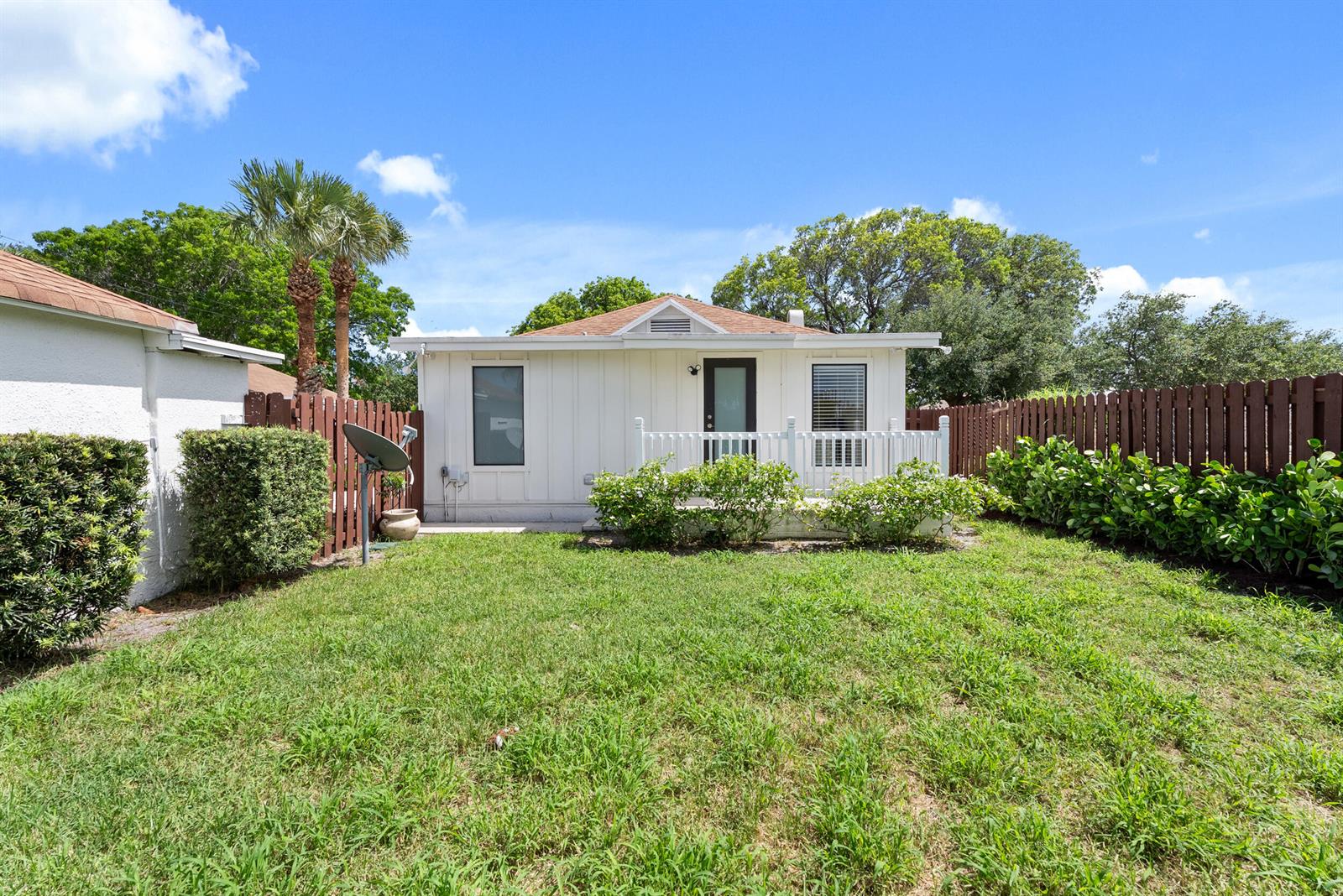A white single-story house with a small deck and backyard enclosed by a wooden fence — 517 55th Street, West Palm Beach FL 33407, WEST PALM BEACH, FL