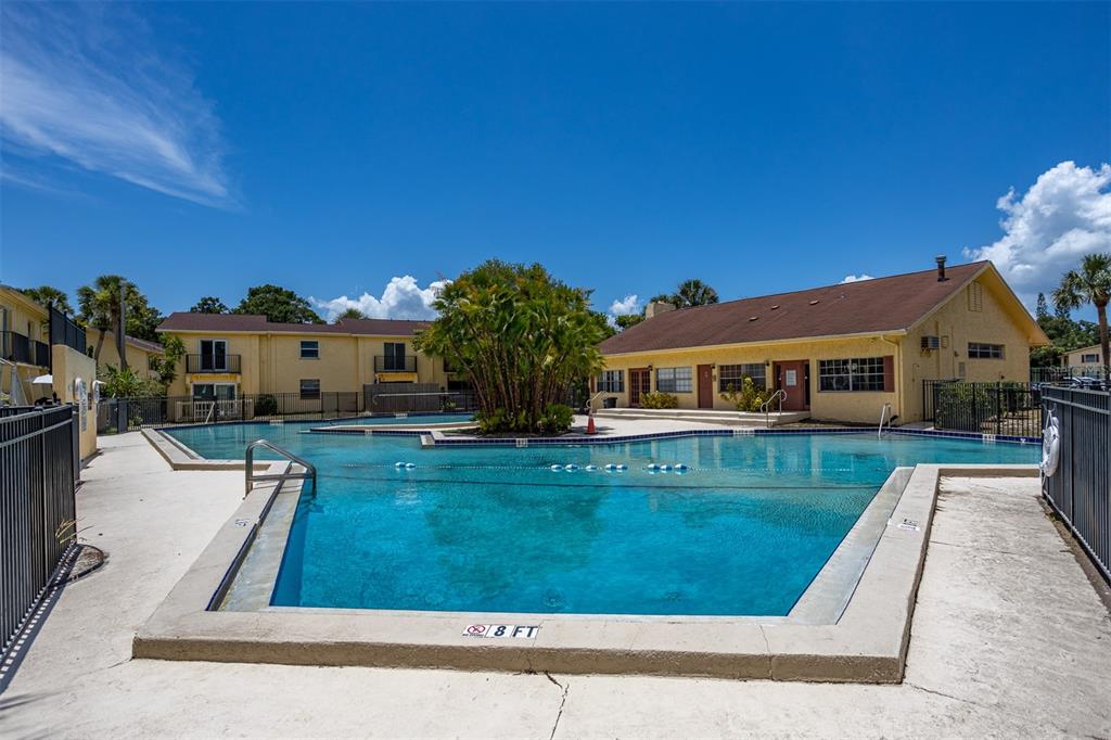 An outdoor swimming pool with an eight-foot depth marker sits in front of apartment buildings — 7612 NACIDO COURT, TAMPA, FL