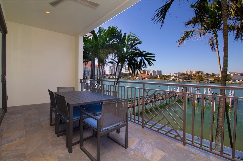 A covered balcony features a dining set, tile flooring, and a metal railing overlooking water — 158 BRIGHTWATER DRIVE UNIT 1, CLEARWATER BEACH, FL