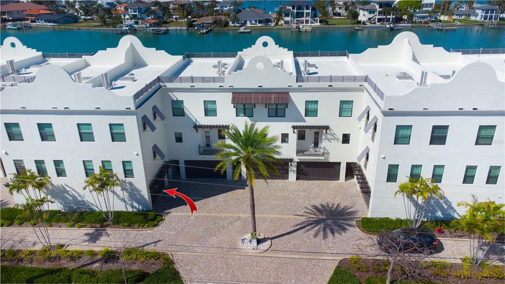 An aerial view of a white multi-story townhouse complex with a paved courtyard and palm trees — 158 BRIGHTWATER DRIVE UNIT 1, CLEARWATER BEACH, FL
