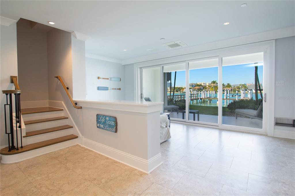 A room with tile floors, a staircase, and sliding glass doors overlooking a boat dock — 158 BRIGHTWATER DRIVE UNIT 1, CLEARWATER BEACH, FL