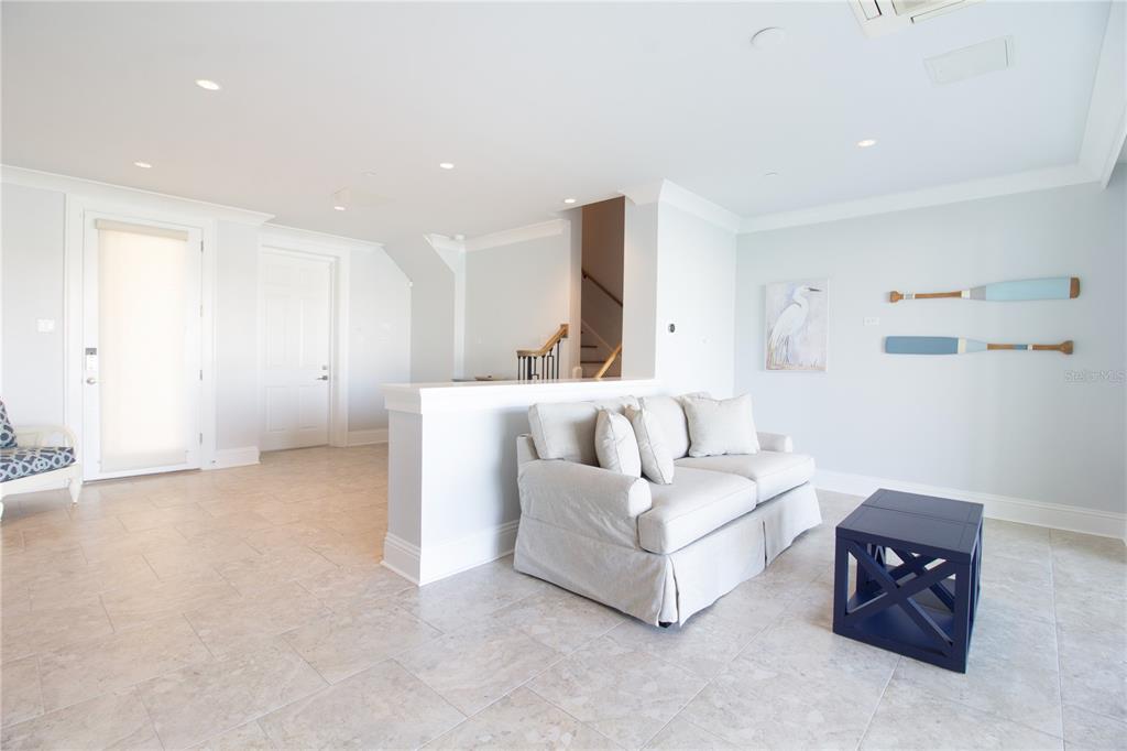 A living room features a light-colored sofa, a blue side table, and coastal wall decor — 158 BRIGHTWATER DRIVE UNIT 1, CLEARWATER BEACH, FL