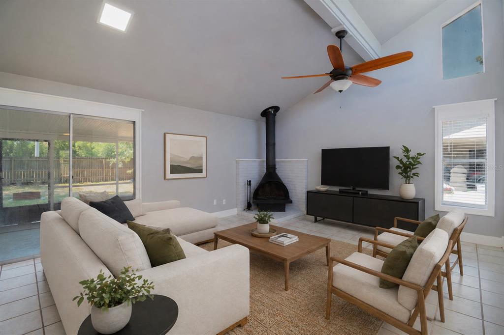 A living room features a vaulted ceiling, a corner fireplace, and a large sectional sofa — 2411 NW 54TH AVENUE, GAINESVILLE, FL