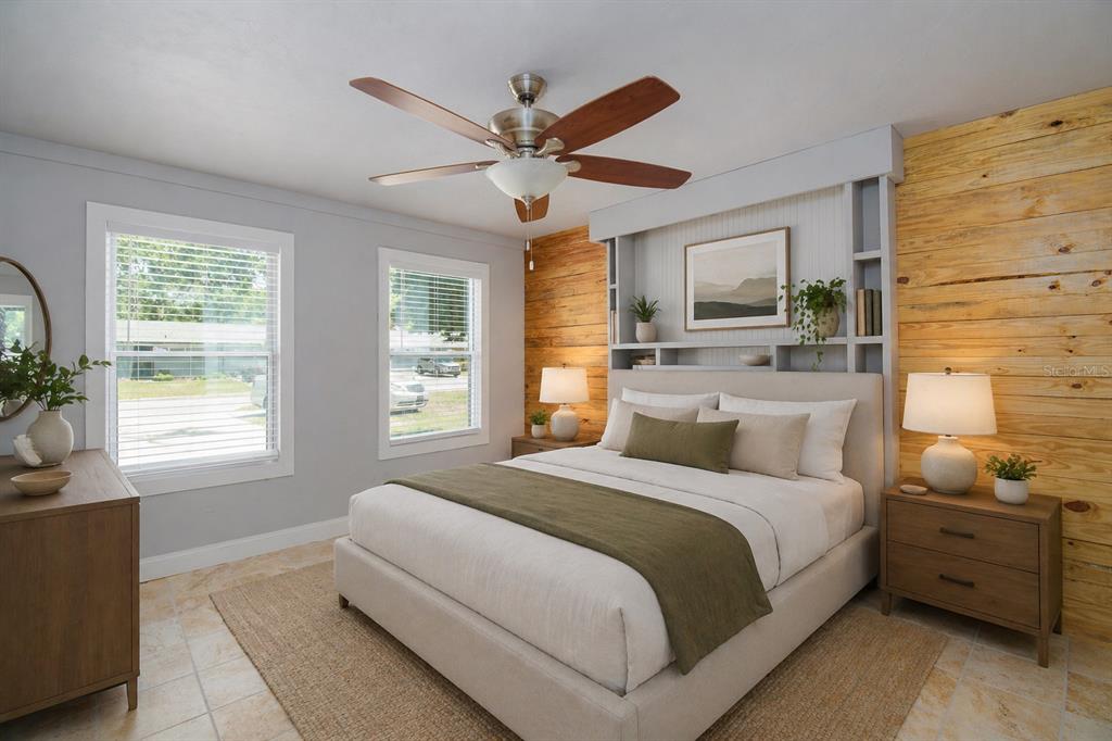 A bedroom features a wood-paneled accent wall, built-in shelving, a ceiling fan, and two windows — 2411 NW 54TH AVENUE, GAINESVILLE, FL