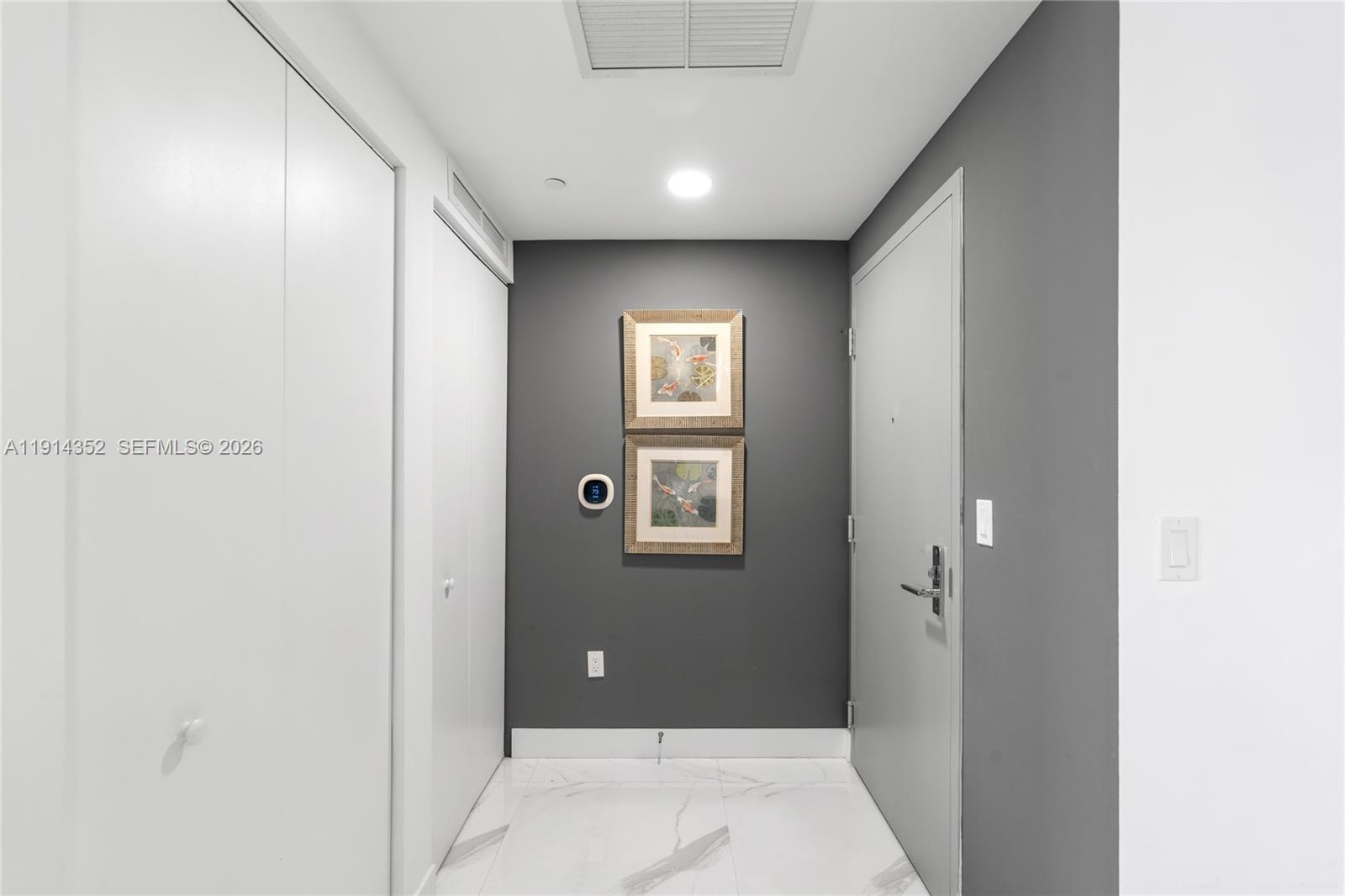 A hallway features white marble flooring, a dark gray accent wall, and two framed pictures — 488 NE 18th St # 4309, Miami FL 33132, MIAMI, FL